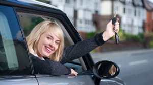 When is the best time of year to buy a new car woman smiling with car keys
